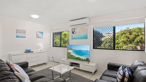 Un salon moderne avec un téléviseur à écran plat, un canapé, une table basse et un meuble blanc.
