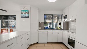 Une cuisine moderne avec des armoires blanches, un lave-vaisselle intégré et une fenêtre donnant sur la rue.