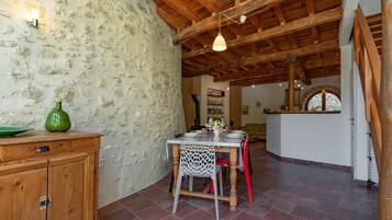 Un comedor rústico con una mesa de madera, sillas y una pared de piedra.