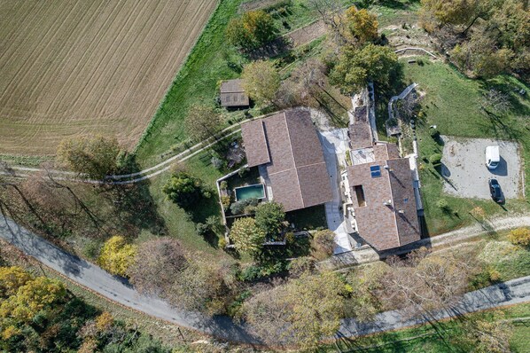 Vue aérienne d’une maison avec un toit en pente, une piscine et une allée.