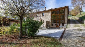 A stone building with a glass extension, a gravel driveway, and a tree in the foreground.