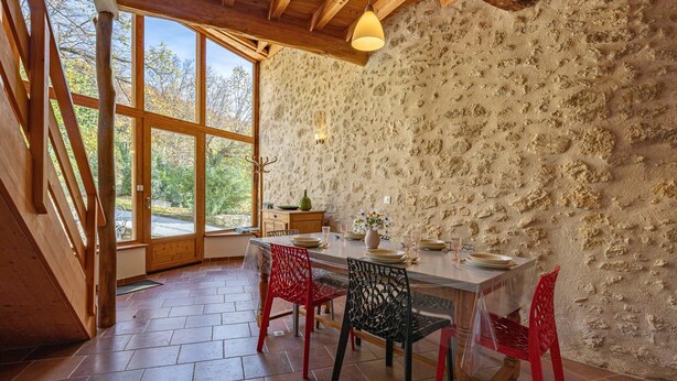 A dining area with a stone wall, wooden ceiling, and a large window.