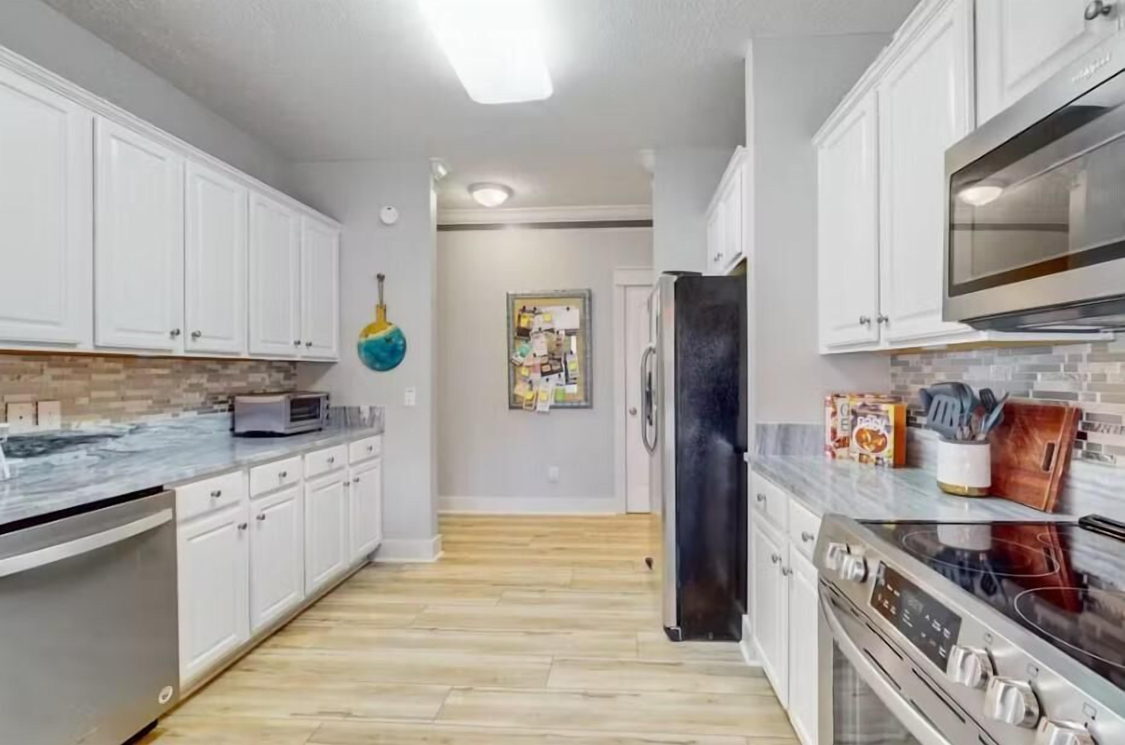 Una cocina moderna con gabinetes blancos, un refrigerador negro, un microondas y una estufa.