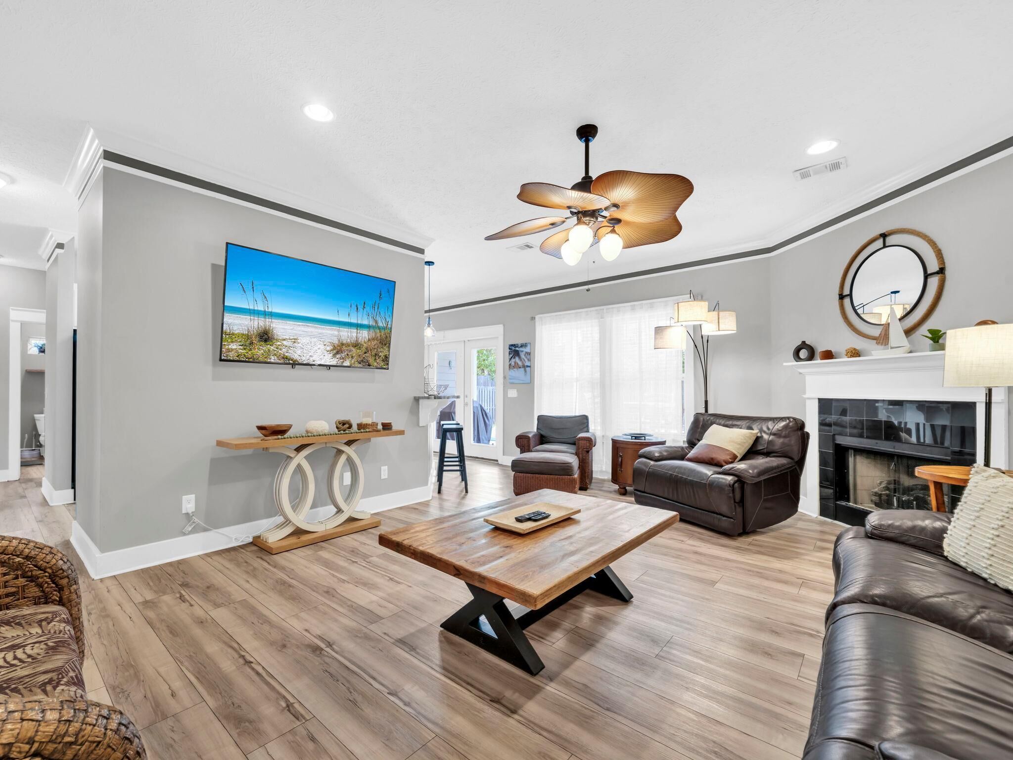 A spacious living room with a wooden floor, a leather sofa, a coffee table, and a fireplace.