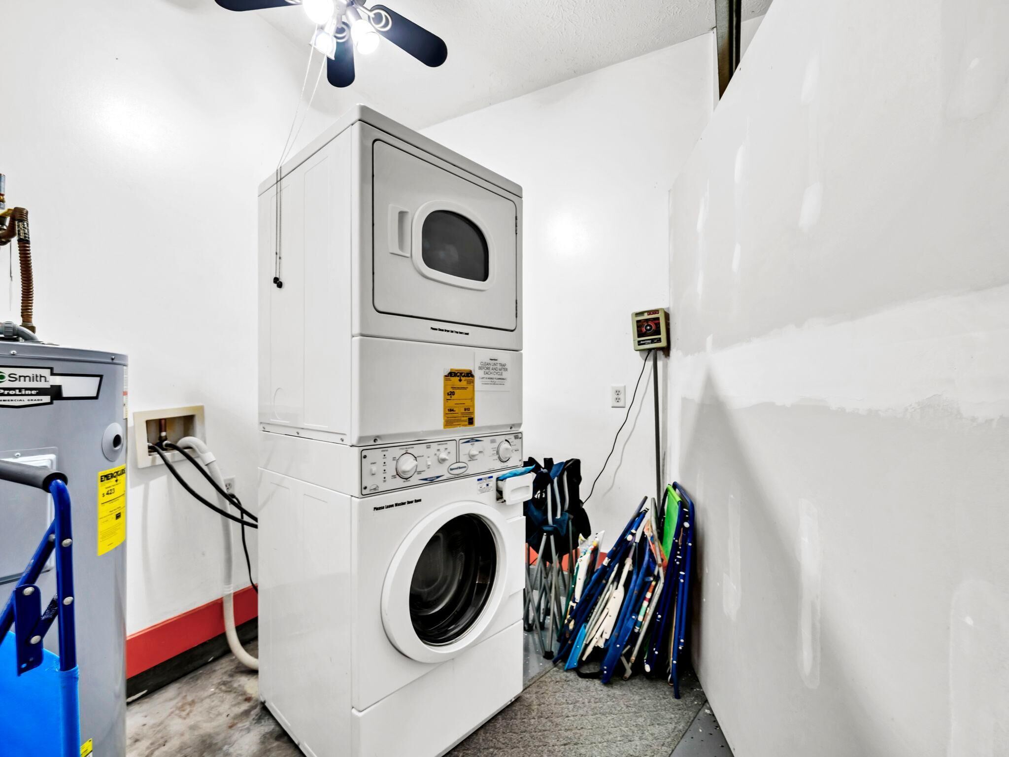 A laundry room with a stacked washer and dryer, a power outlet, and a ceiling fan.