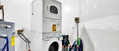 A laundry room with a stacked washer and dryer, a power outlet, and a ceiling fan.