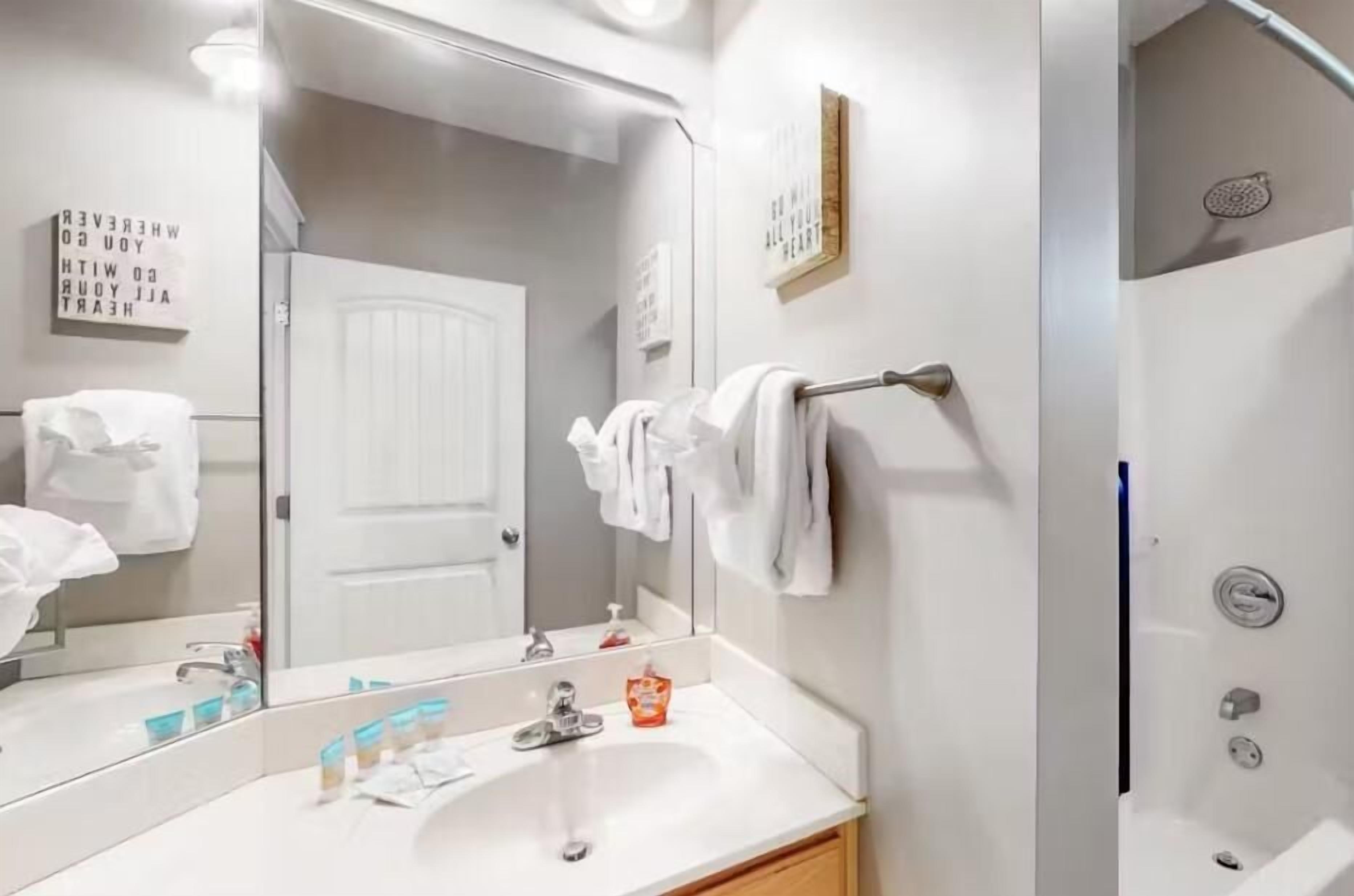 Un bagno moderno con un grande specchio, un lavandino bianco e uno spazio doccia.
