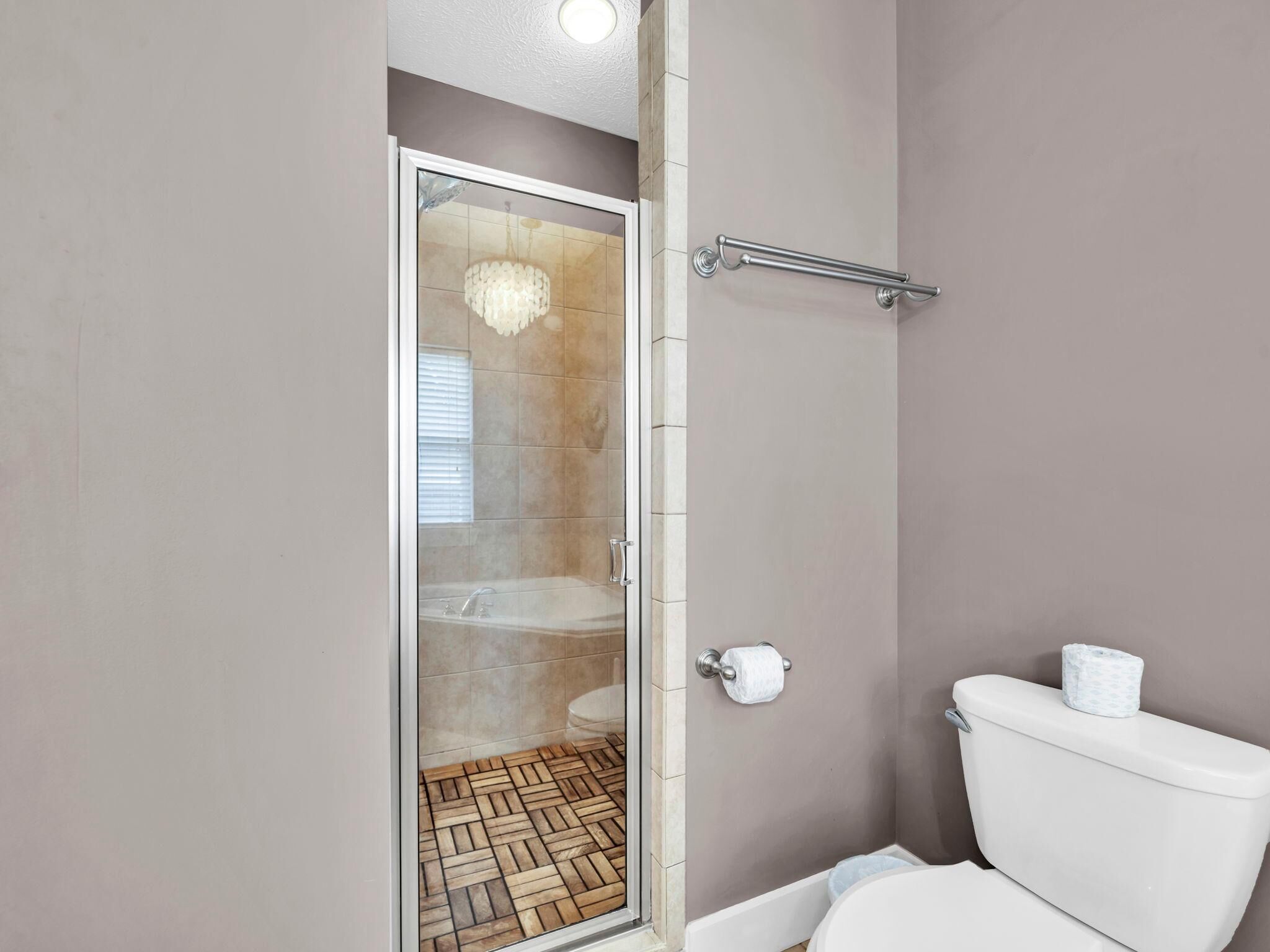 A bathroom with a glass shower enclosure, a toilet, and a towel rack.