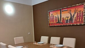 A dining room with a round wooden table, six chairs, and a painting on the wall. - FAMILY APARTMENT VERY CLOSE TO SAN GIULIANO HOSPITAL (Novara)