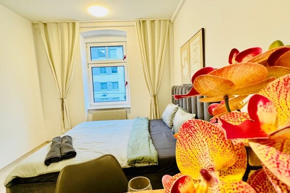 A hotel room with a bed, a window, curtains, and a chair.