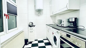 Una cocina funcional con lavadora, microondas y hervidor.