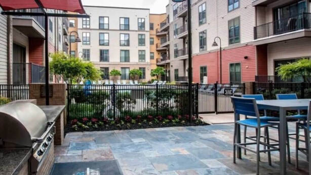 Un patio con una parrilla, mobiliario exterior y una piscina.