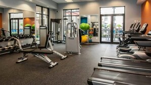 Un gimnasio con cintas de correr, máquinas de pesas y pelotas de ejercicio.