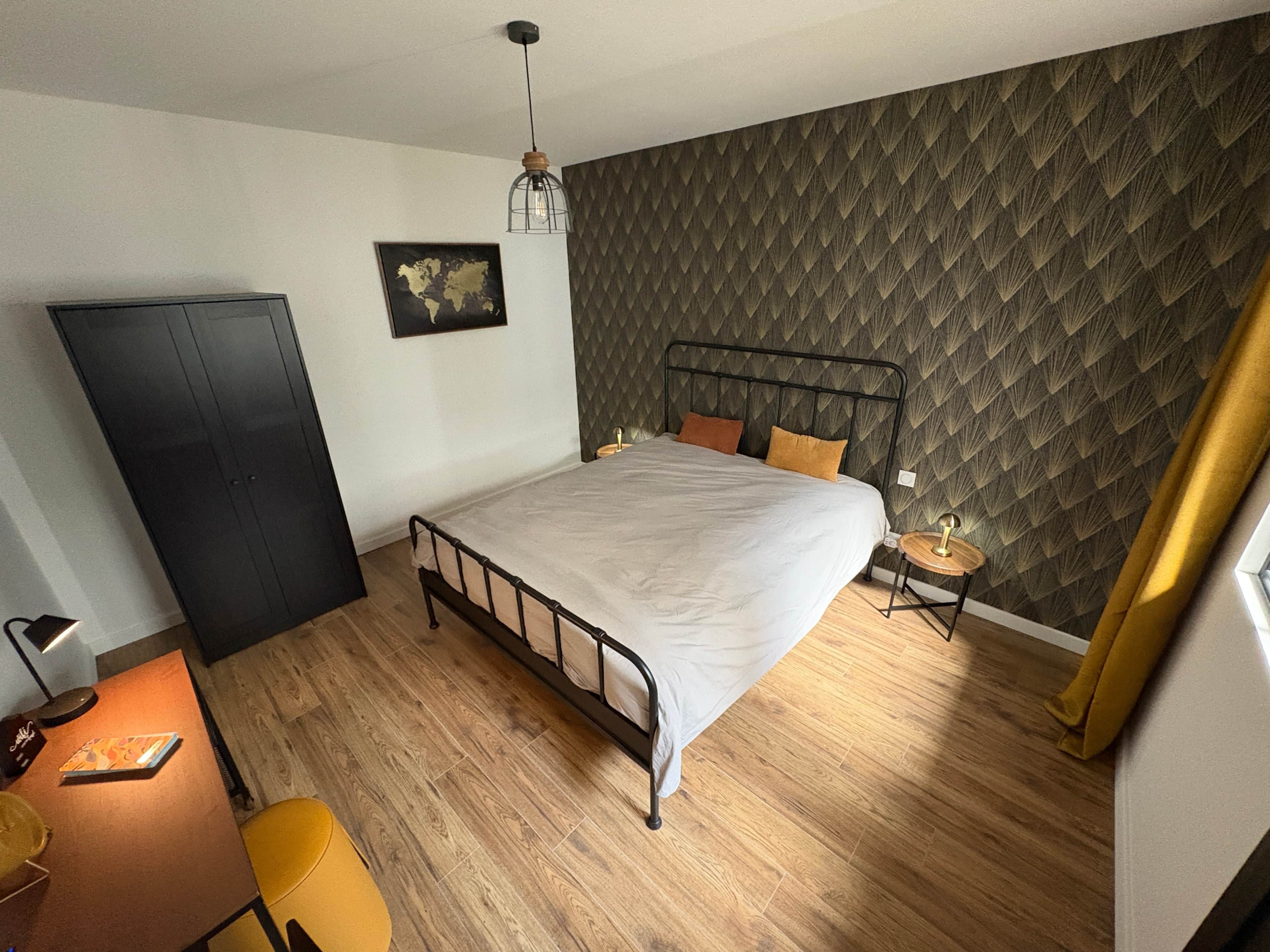 Ein Schlafzimmer mit einem Bett, einem Kleiderschrank, einem Schreibtisch und einem Stuhl.
