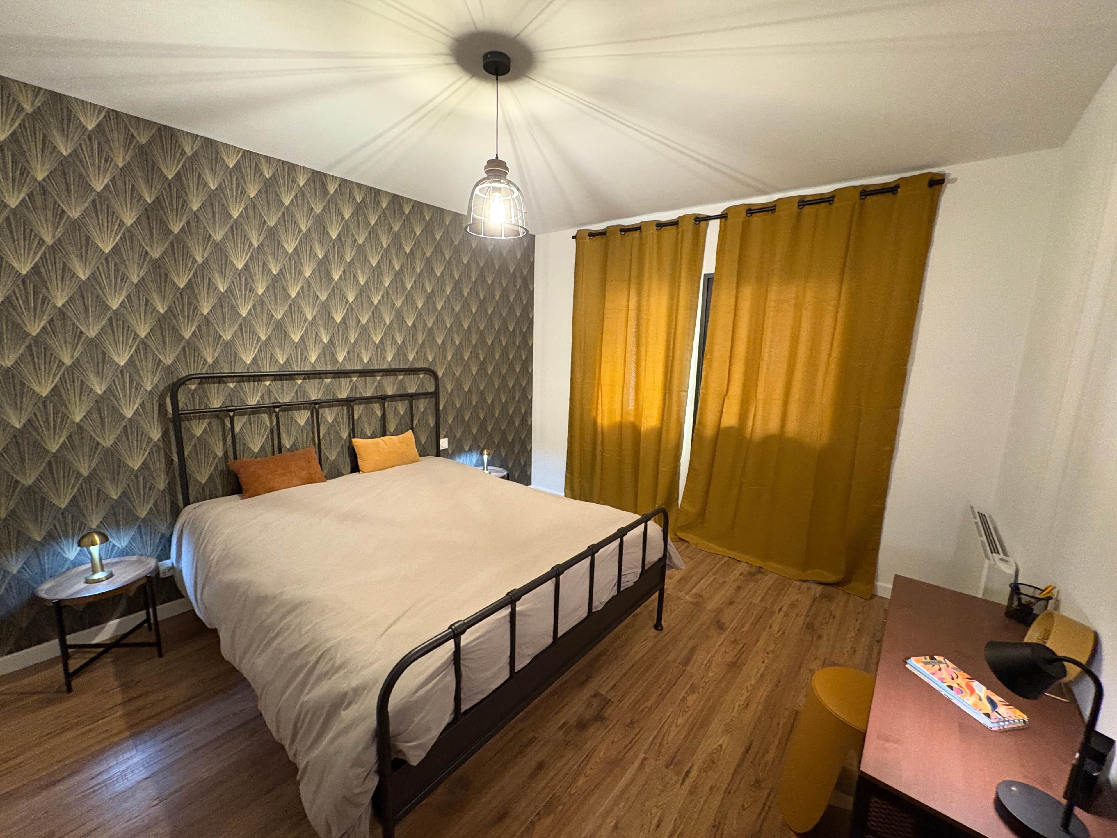 A bedroom with a bed, a desk, a chair, a lamp, and curtains.