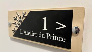 Une enseigne noire et beige, portant le numéro 1 et l’inscription « L’Atelier du Prince », est fixée à un mur.