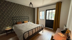 Une chambre à coucher avec un lit, un bureau, une chaise, une lampe et une fenêtre avec des rideaux.