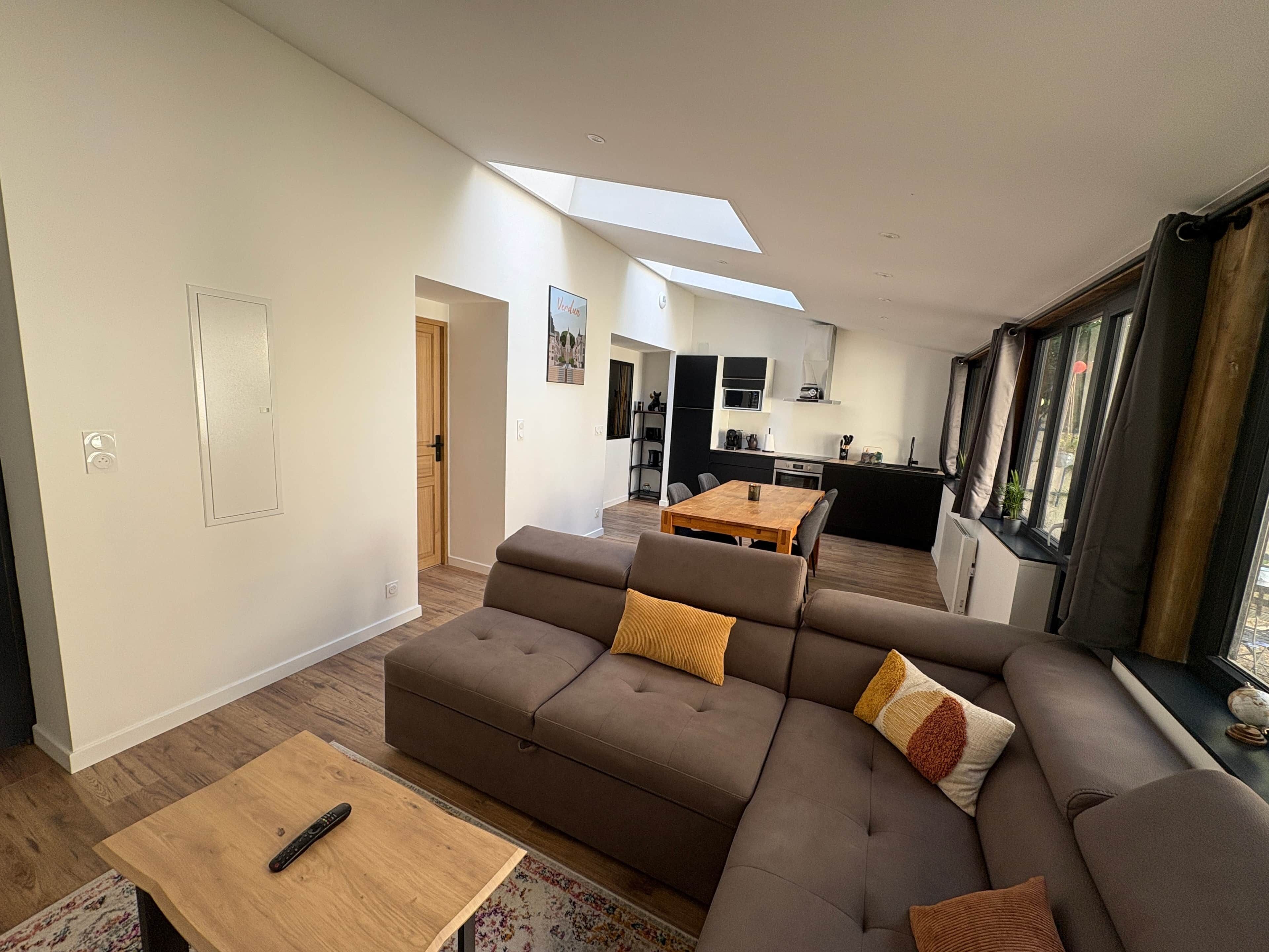 A modern living room with a sofa, a wooden coffee table, and a dining area with a table and chairs.