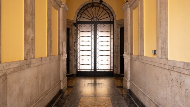A hallway with a double door, yellow walls, and a tiled floor.