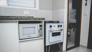 A compact kitchen with a microwave and a built-in oven. - Tima Kitnet Prox Unifei com Wi-fi e Smart TV (Itajuba)