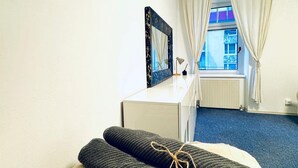 Een hotelkamer met een bed, een bureau, een raam met gordijnen en een radiator.