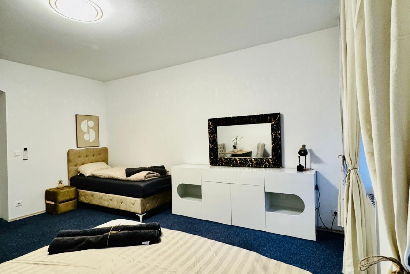 Quarto com cama, penteadeira, espelho e cortina.