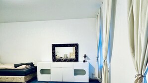 Een slaapkamer met een bed, een witte kaptafel met spiegel en een gordijn.