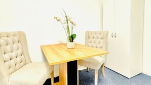 Een kamer met een houten tafel, twee stoelen, een witte kast en een potplant.