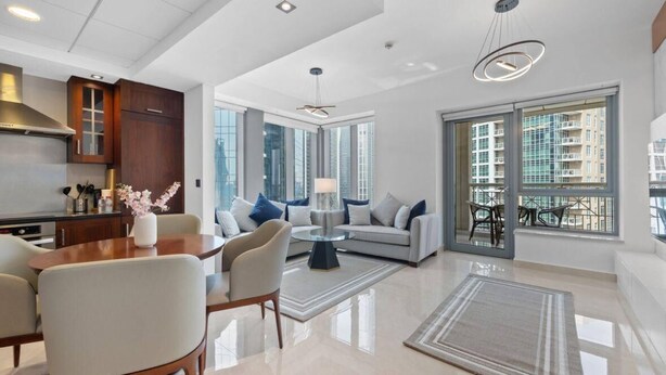 A modern living room with a sofa, chairs, a coffee table, and a dining area with a table and chairs. - SIMPLY COMFORT Luxury Burj Khalifa & Fountain View Apartments Steps to Dubai Mall (Dubai)