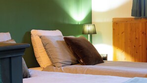 Ein ordentlich bezogenes Bett mit Kissen und Decke, ein Nachttisch, eine Lampe und ein Holzschrank.