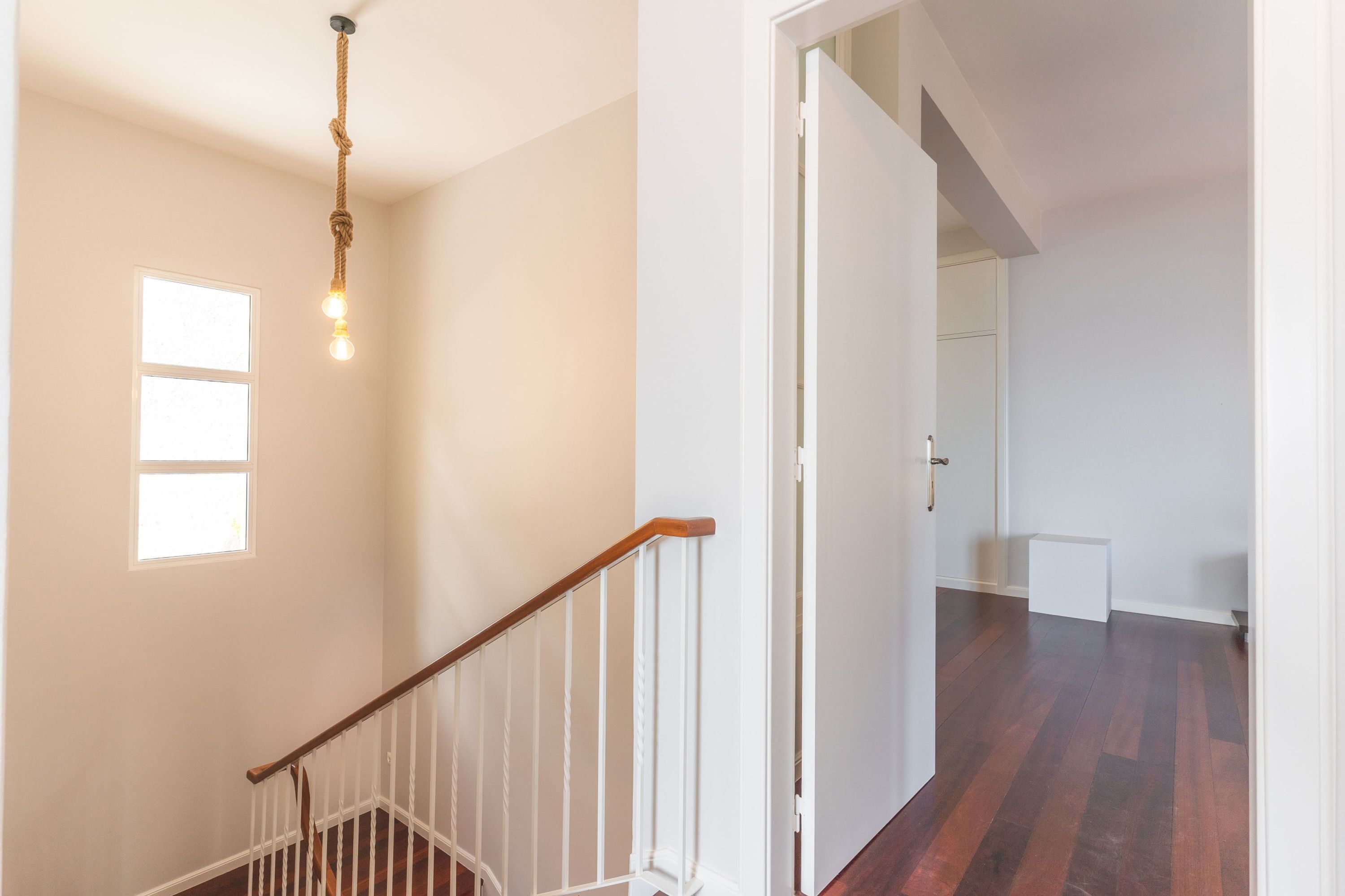 A staircase with a wooden handrail and a light fixture above it.