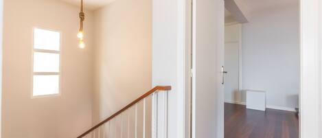 A staircase with a wooden handrail and a light fixture above it.