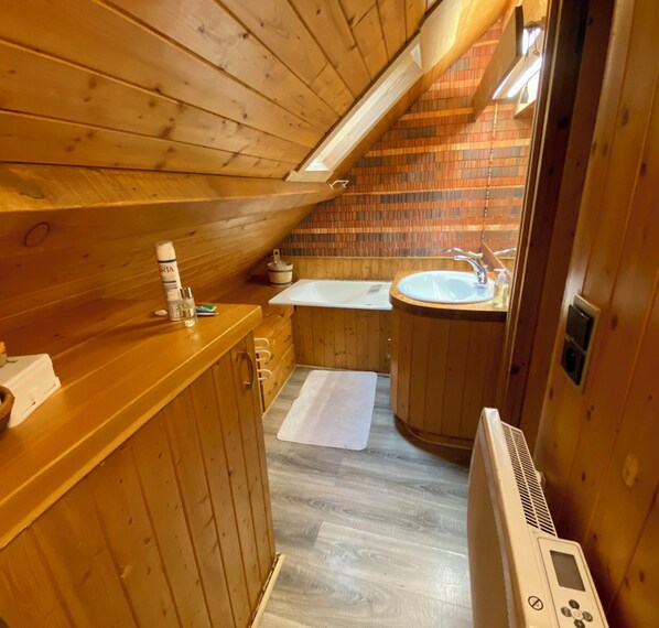 A wooden cabin bathroom with a sink, a towel, and a heater.