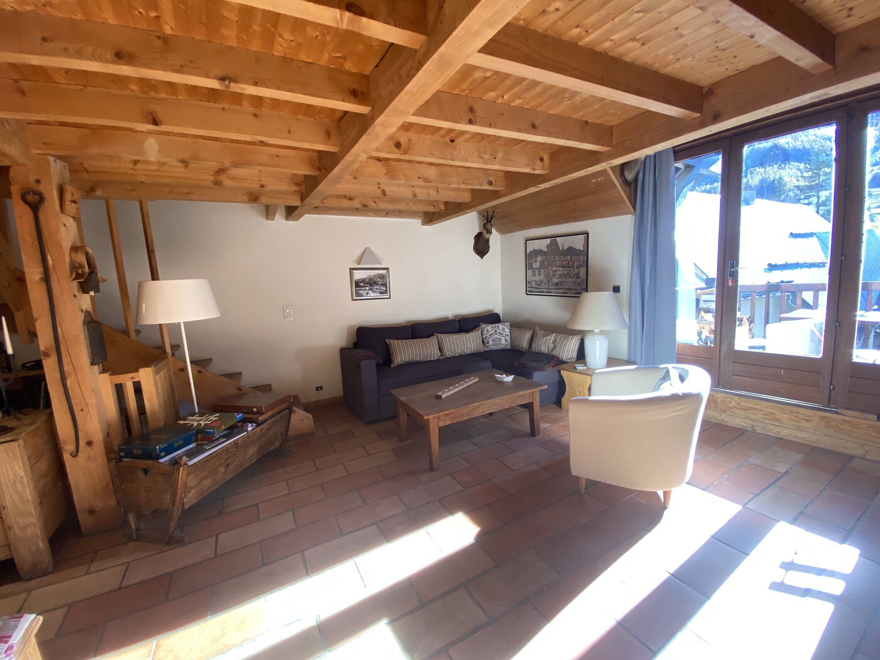 Ein Holzinnenraum mit einer Couch, einem Tisch und einem Stuhl. Ein Fenster bietet Blick ins Freie.