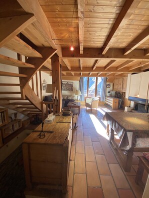 A rustic wooden interior with a staircase, a dining table, and a kitchen area.