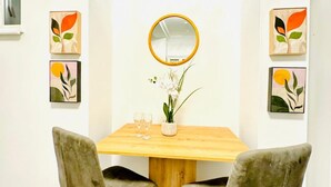 Un comedor con una mesa de madera, dos sillas, un espejo y decoración en la pared.
