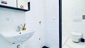 Un baño moderno con lavamanos, espejo y retrete blancos.
