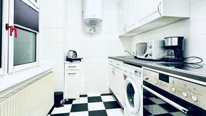 Una cocina compacta equipada con lavadora, cafetera y radiador.