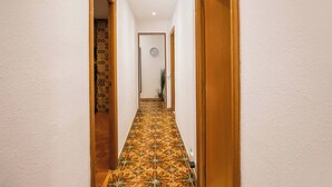 A hallway with patterned floor tiles, wooden doors, and a clock on the wall. - Apartment in Gracia A34PAA1127 (Barcelona)