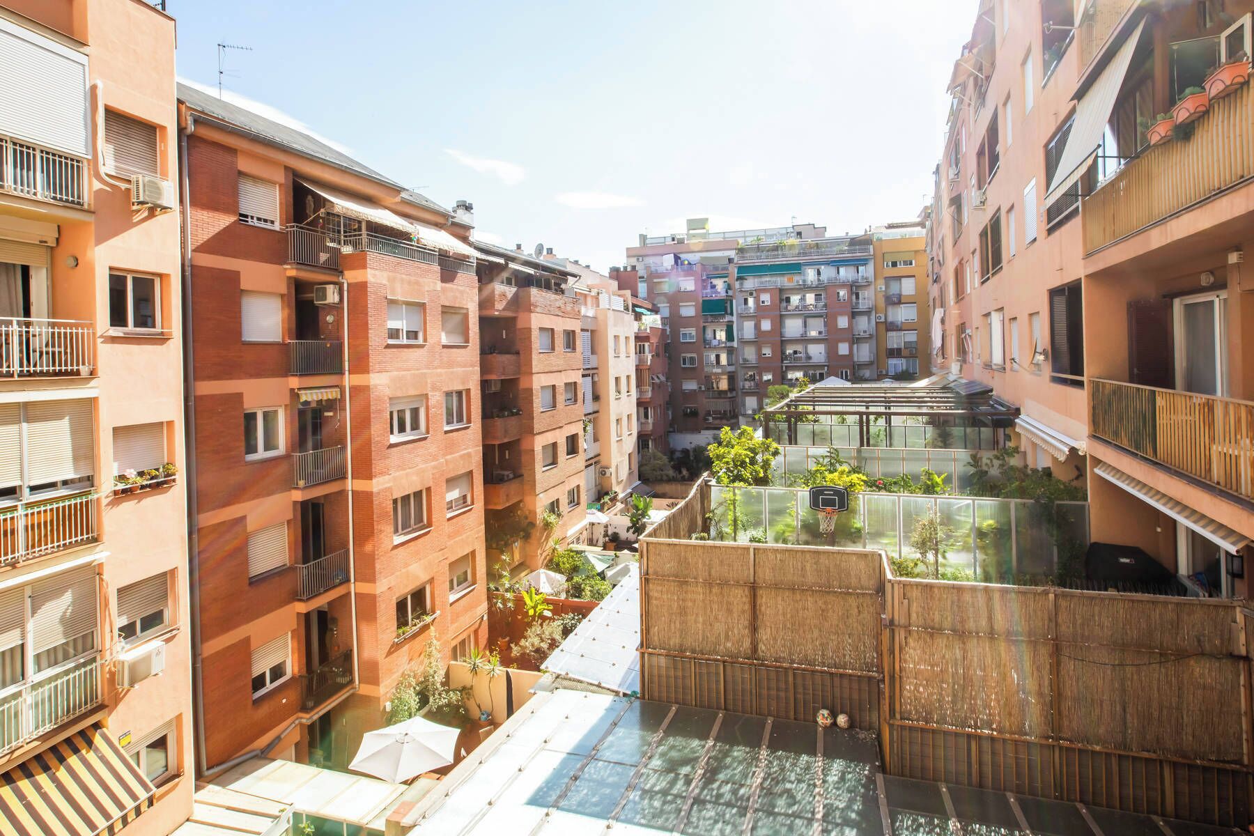 Un edificio residencial con varios balcones, un jardín en la azotea y una terraza con cerramiento de vidrio.