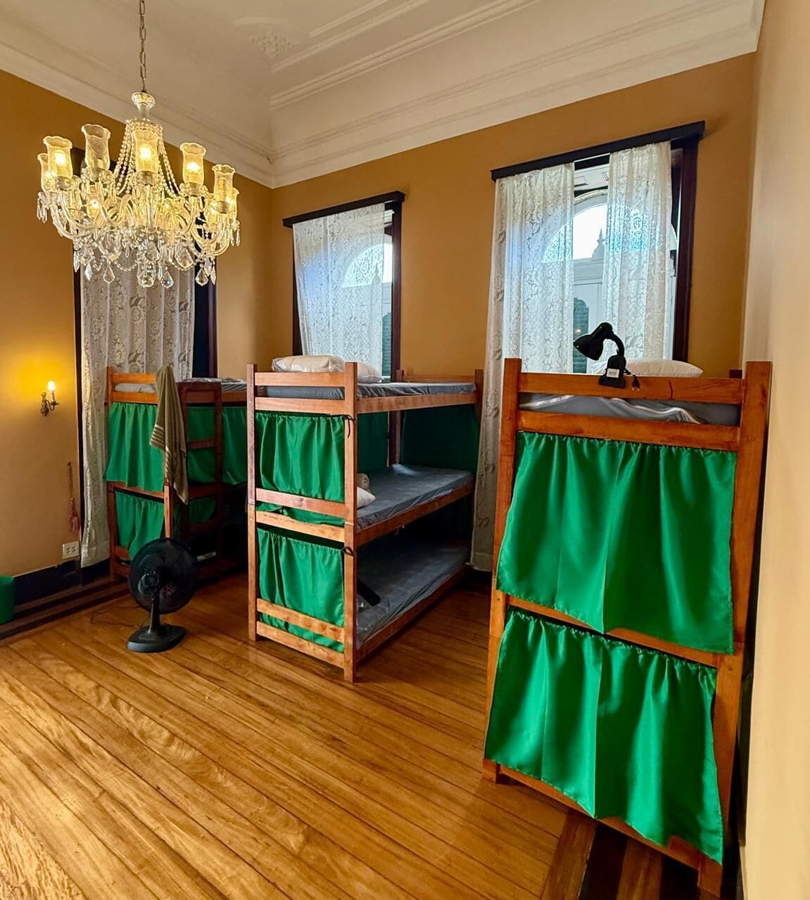A room with bunk beds, a chandelier, and a fan.