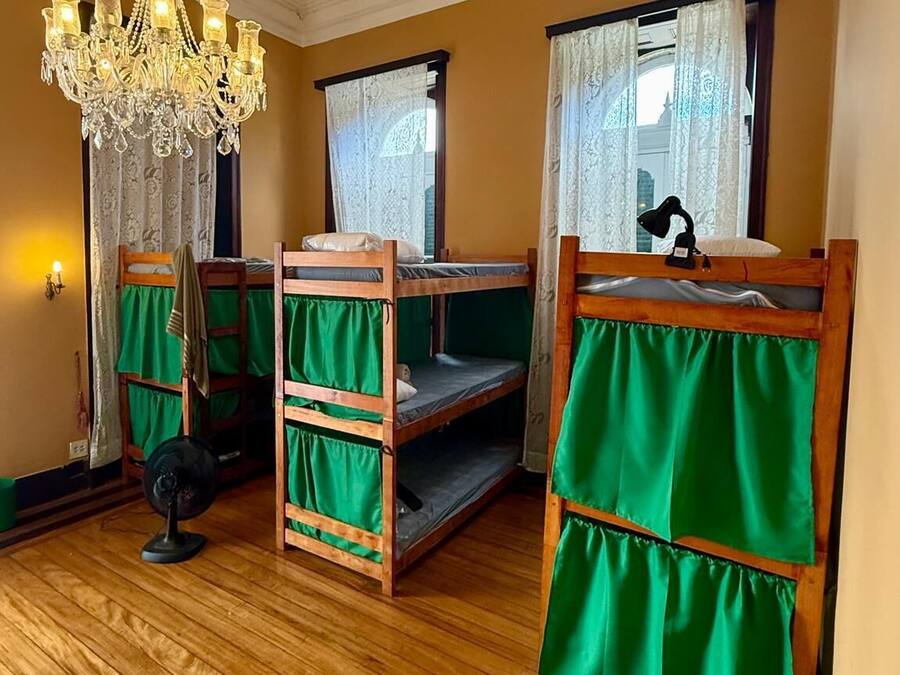 Una habitación con literas, un candelabro y un ventilador.