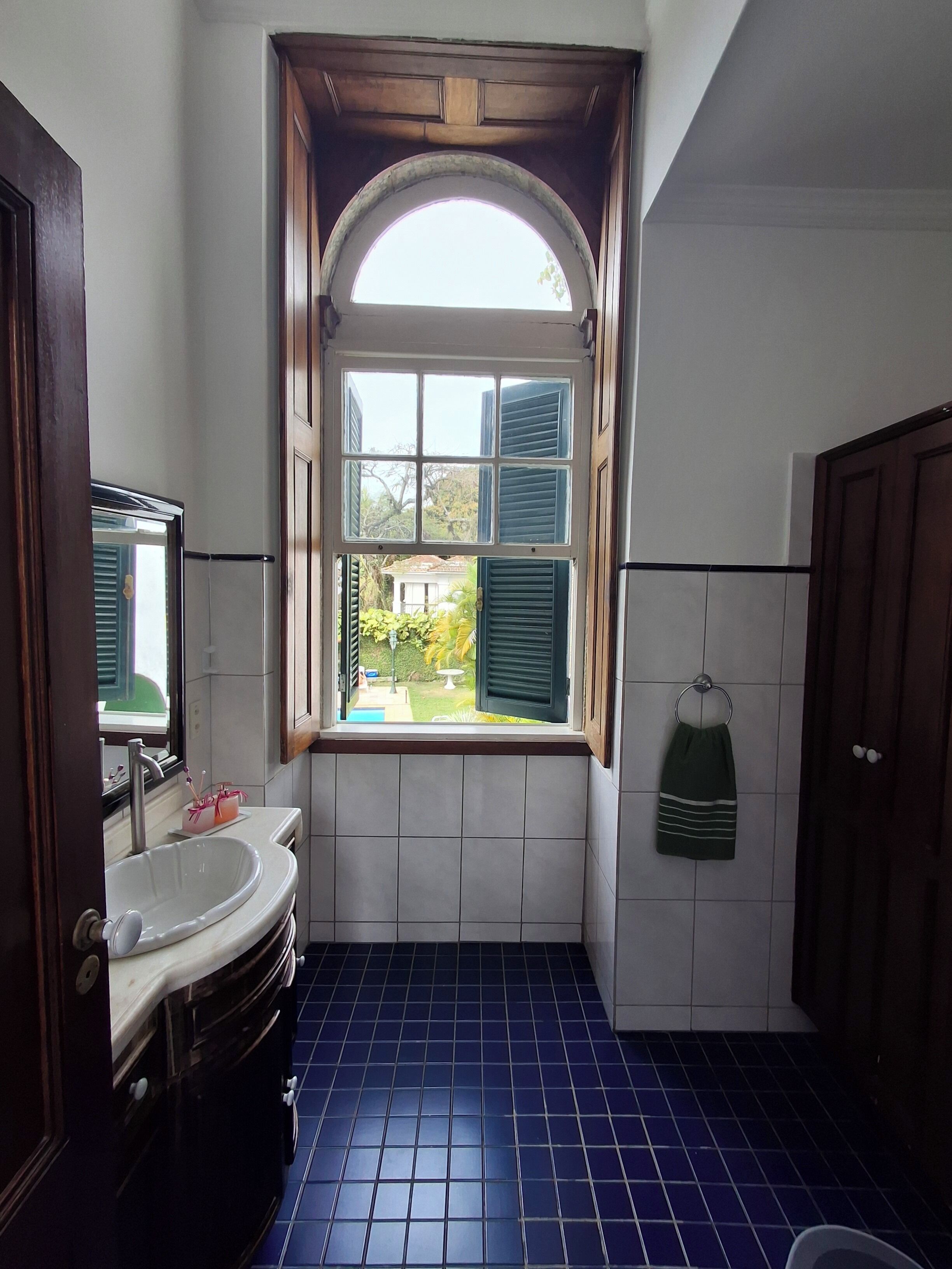 Ein Badezimmer mit Fenster, Waschbecken und einem Handtuch an der Wand.