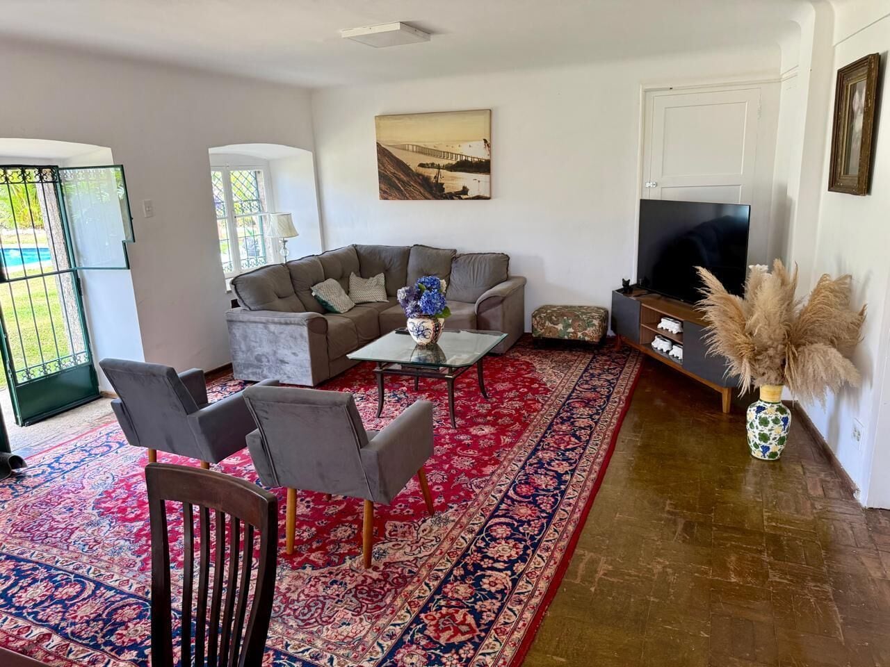 A living room with a sofa, chairs, a coffee table, a TV, and a patterned rug.