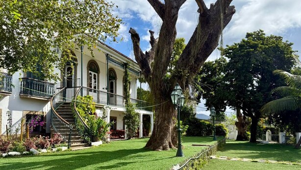 A historic building with a large tree in the front yard, a staircase leading to a balcony, and a well-maintained lawn. - Hostel Casa Aprazível (Rio de Janeiro)