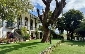 A historic building with a large tree in the front yard, a staircase leading to a balcony, and a well-maintained lawn. - Hostel Casa Aprazível (Rio de Janeiro)