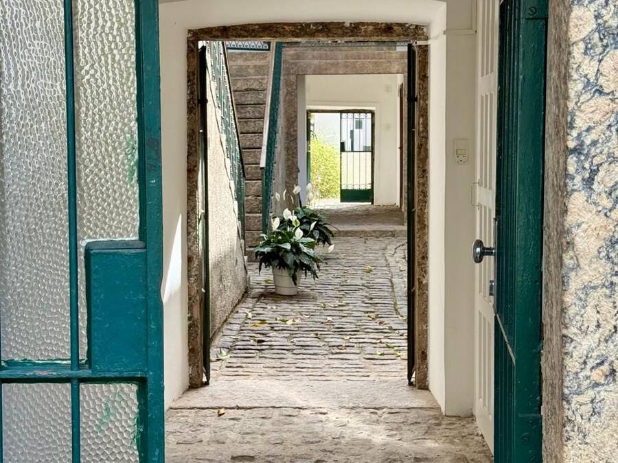 A narrow stone-paved corridor with a staircase leading to a door.