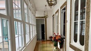 A long, narrow hallway with large windows on one side and doors on the other, leading to a room. - Hostel Casa Aprazível (Rio de Janeiro)