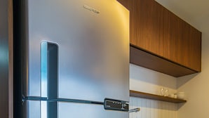 A stainless steel refrigerator with a digital display, wooden cabinets, and a tiled backsplash in the kitchen. - Apto no Butant c Academia e pr Ximo ao Metr (São Paulo)
