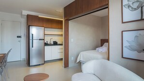 A modern hotel room with a kitchenette, a sofa, and two beds. - Apto no Butant c Academia e pr Ximo ao Metr (São Paulo)